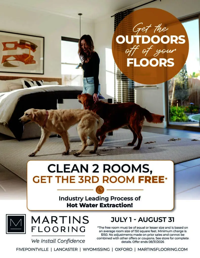 Promotional flyer for Martins Flooring showing a woman with two muddy dogs tracking dirt across a bedroom carpet. Text reads, “Get the outdoors off of your floors,” and advertises clean 2 rooms, get the 3rd room free, using hot water extraction from July 1–August 31.